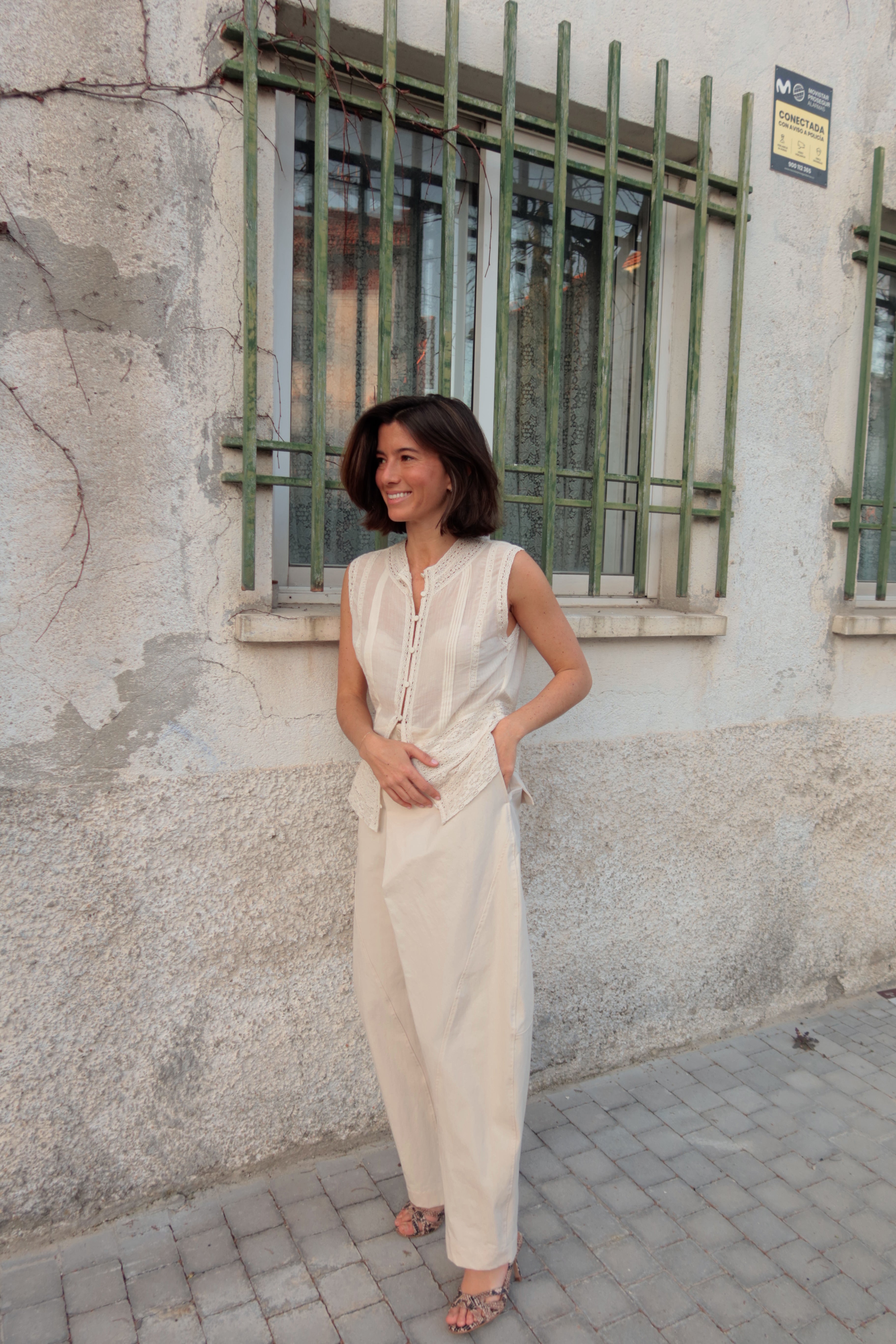 Chica con un look blanco y unas sandalias de piel grabada efecto pitón natural