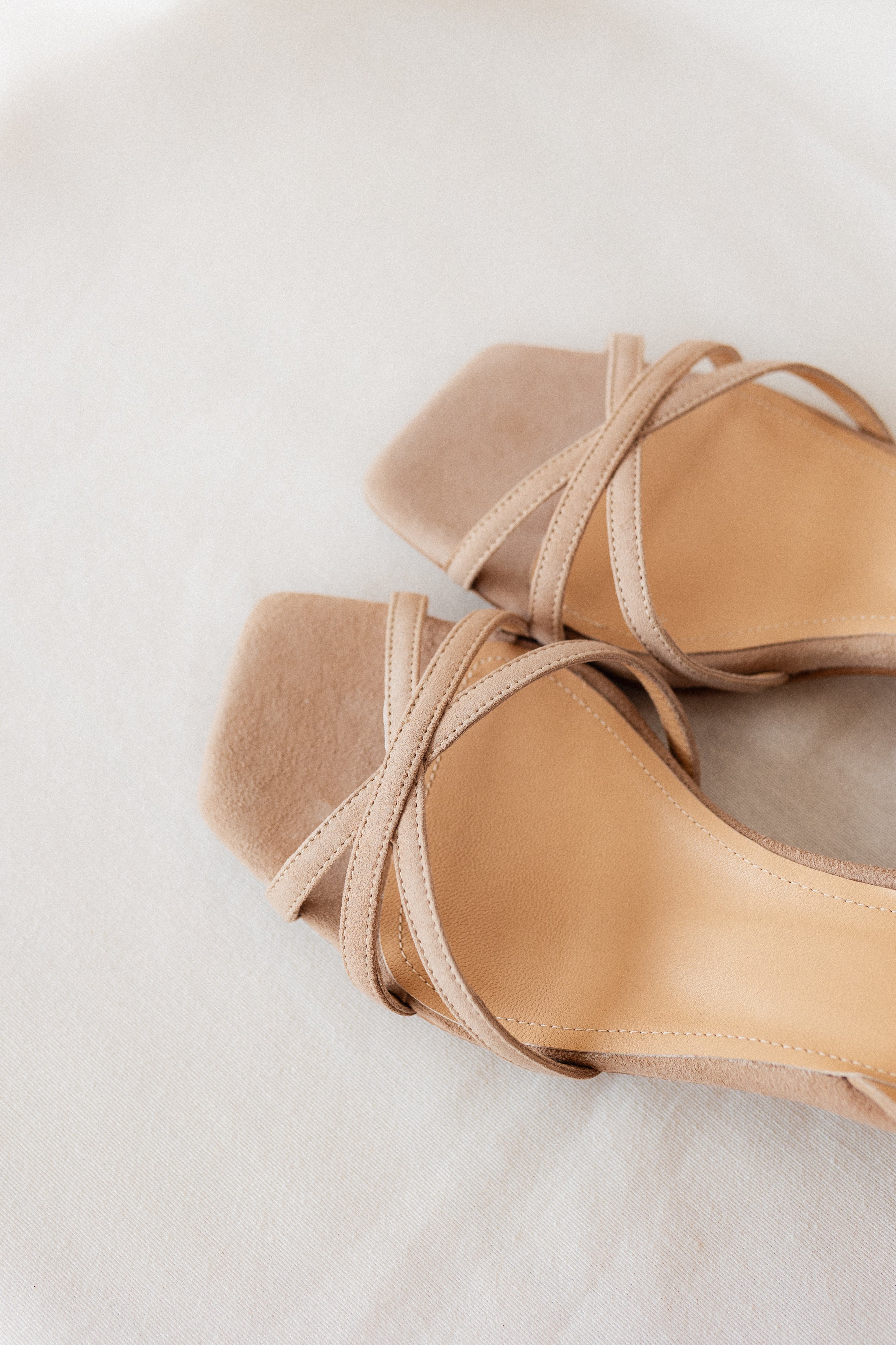 Sandalia elegante de ante beige con tacón cómodo.