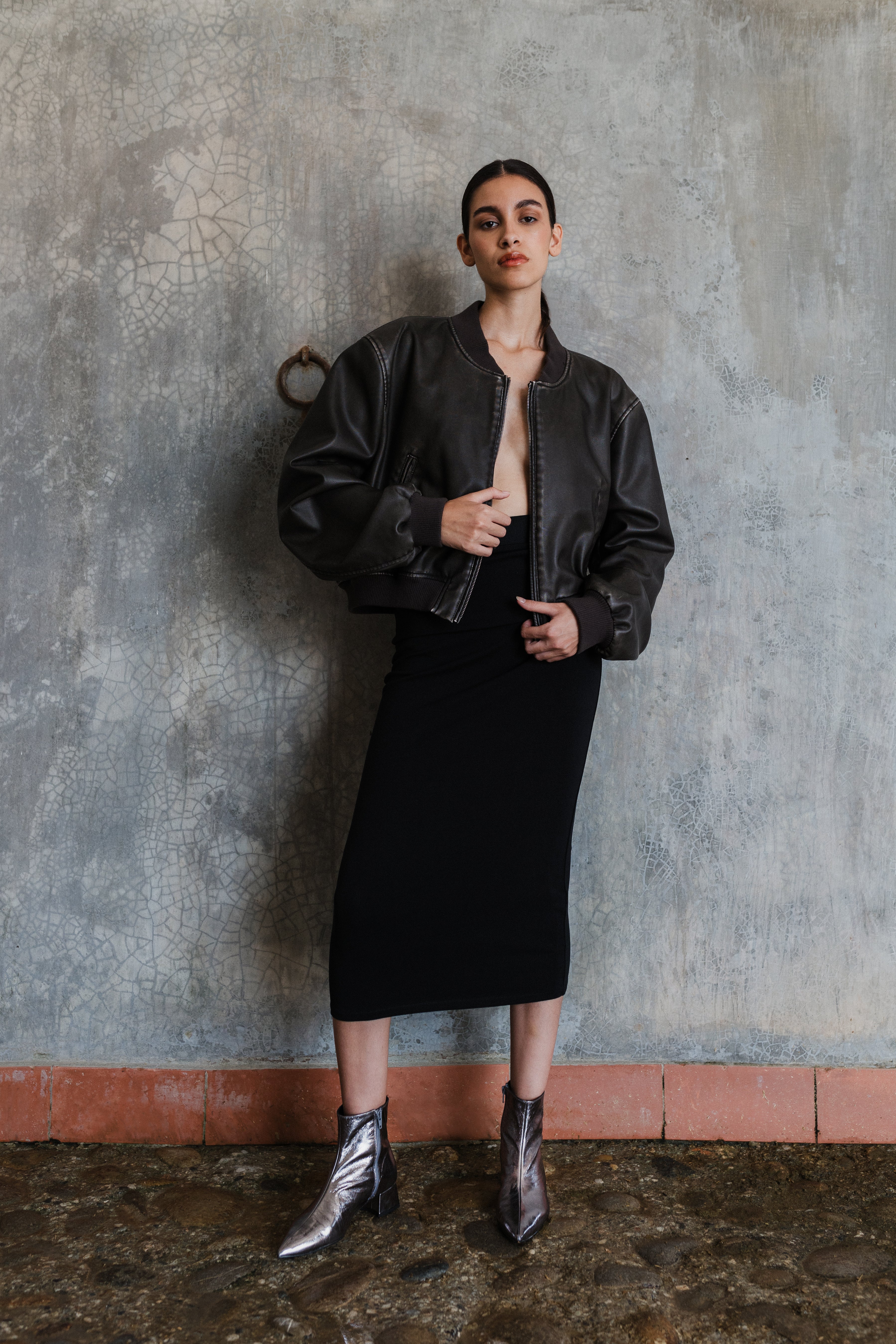 Chica con chaqueta de cuero, falda negra larga y unos botines plomo