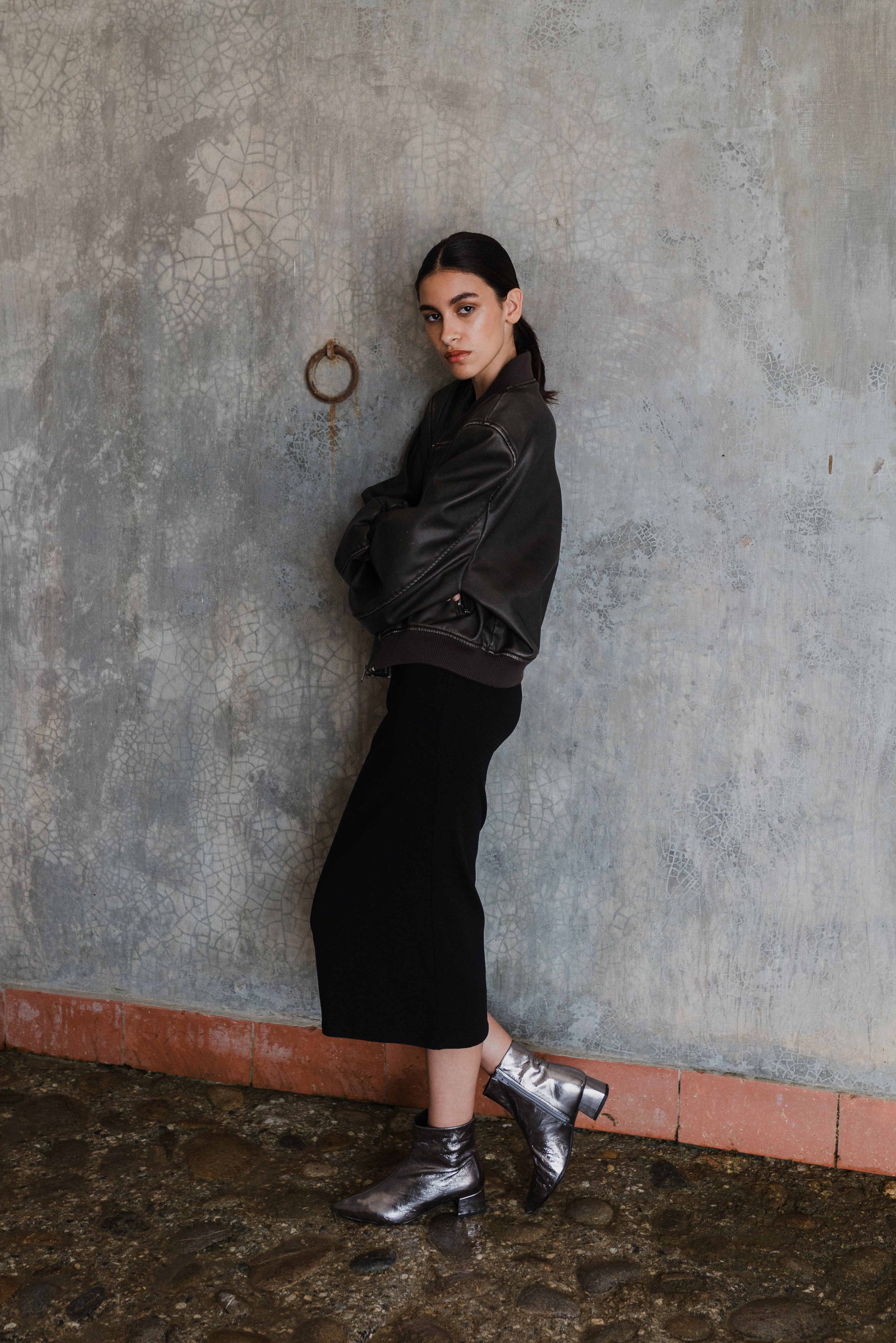 Mujer posando de perfil mirando a cámara con unos botines plomo