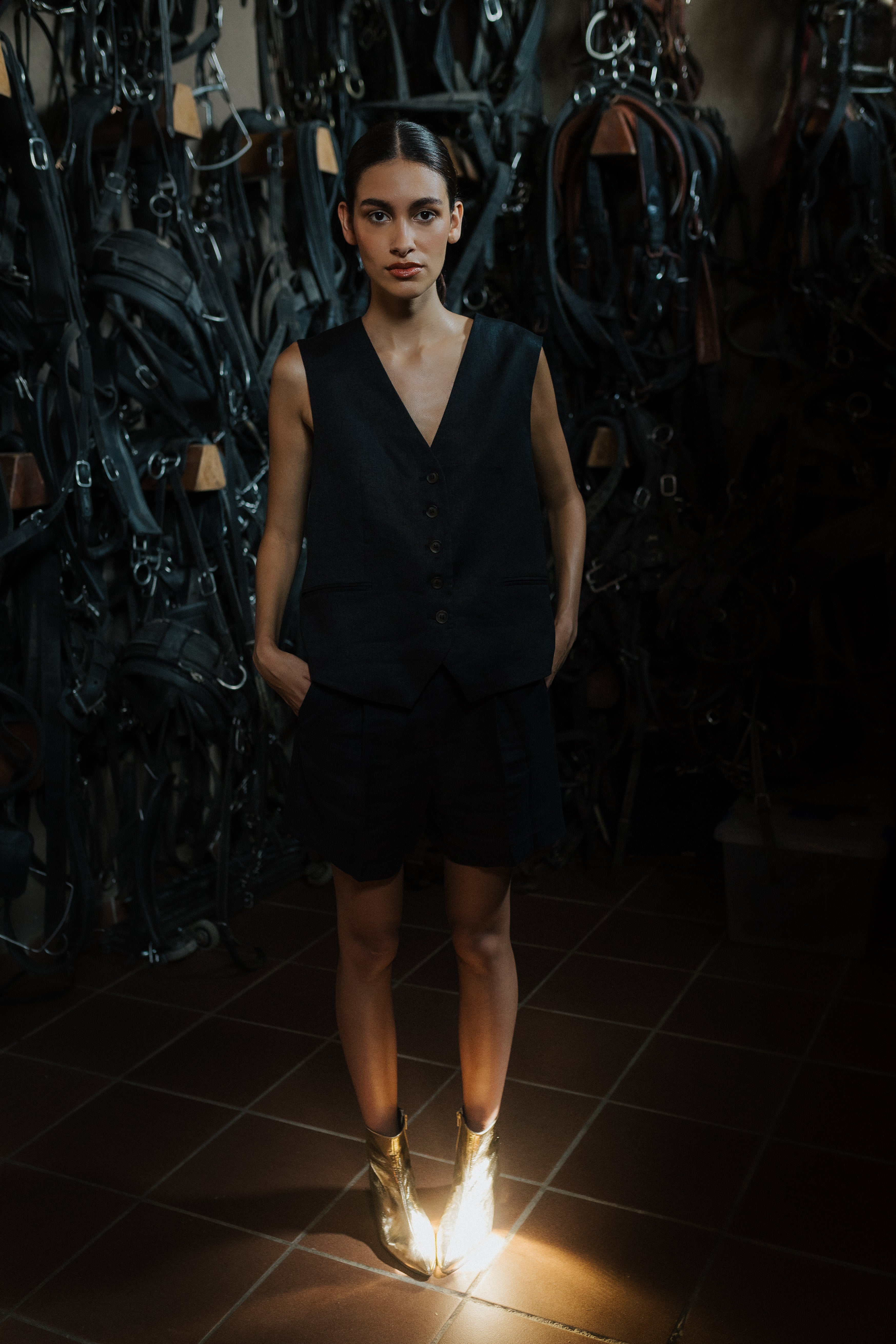 Mujer posando con vestido negro y botines dorados