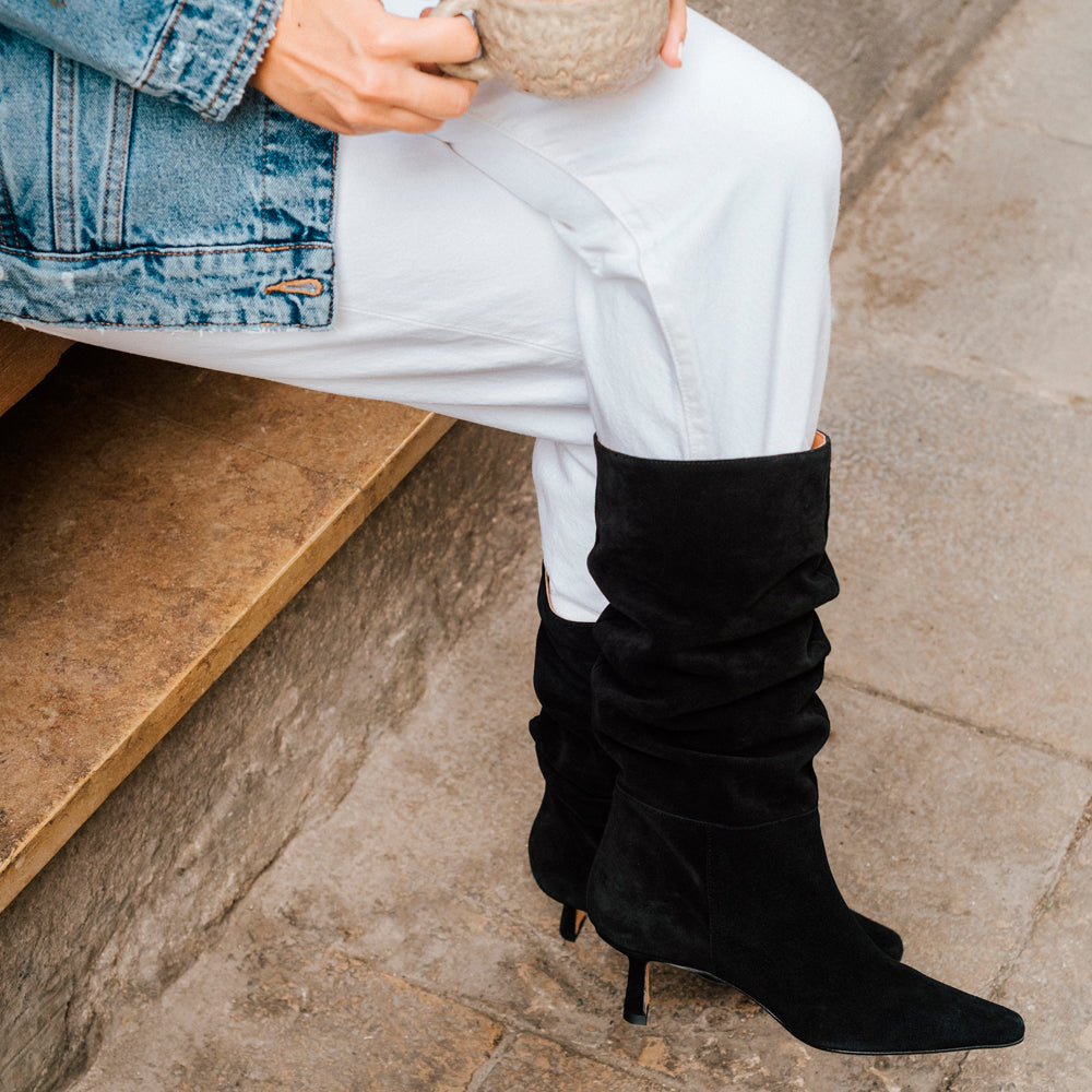Mujer con un outfit de botines negros, pantalones blancos y chaqueta vaquera