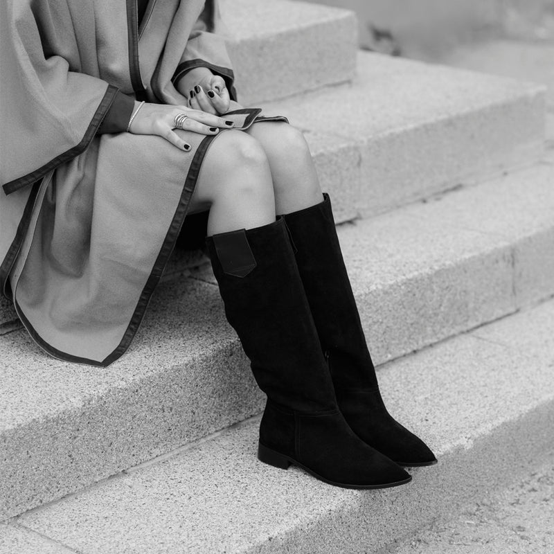 Chica sentada con un par de botas sin tacon hechas en ante negro