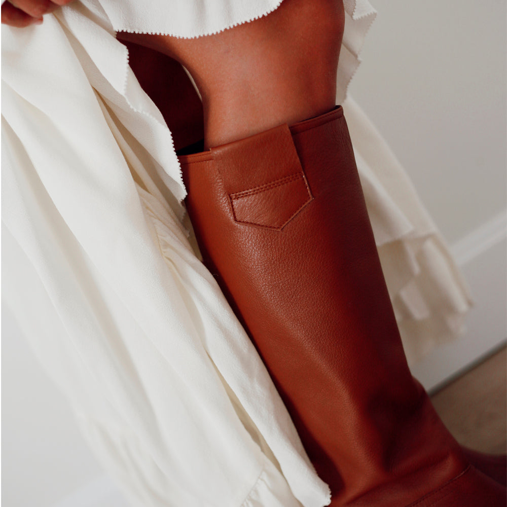 Detalle de una bota para mujer en piel marrón, con poco tacón y caña alta