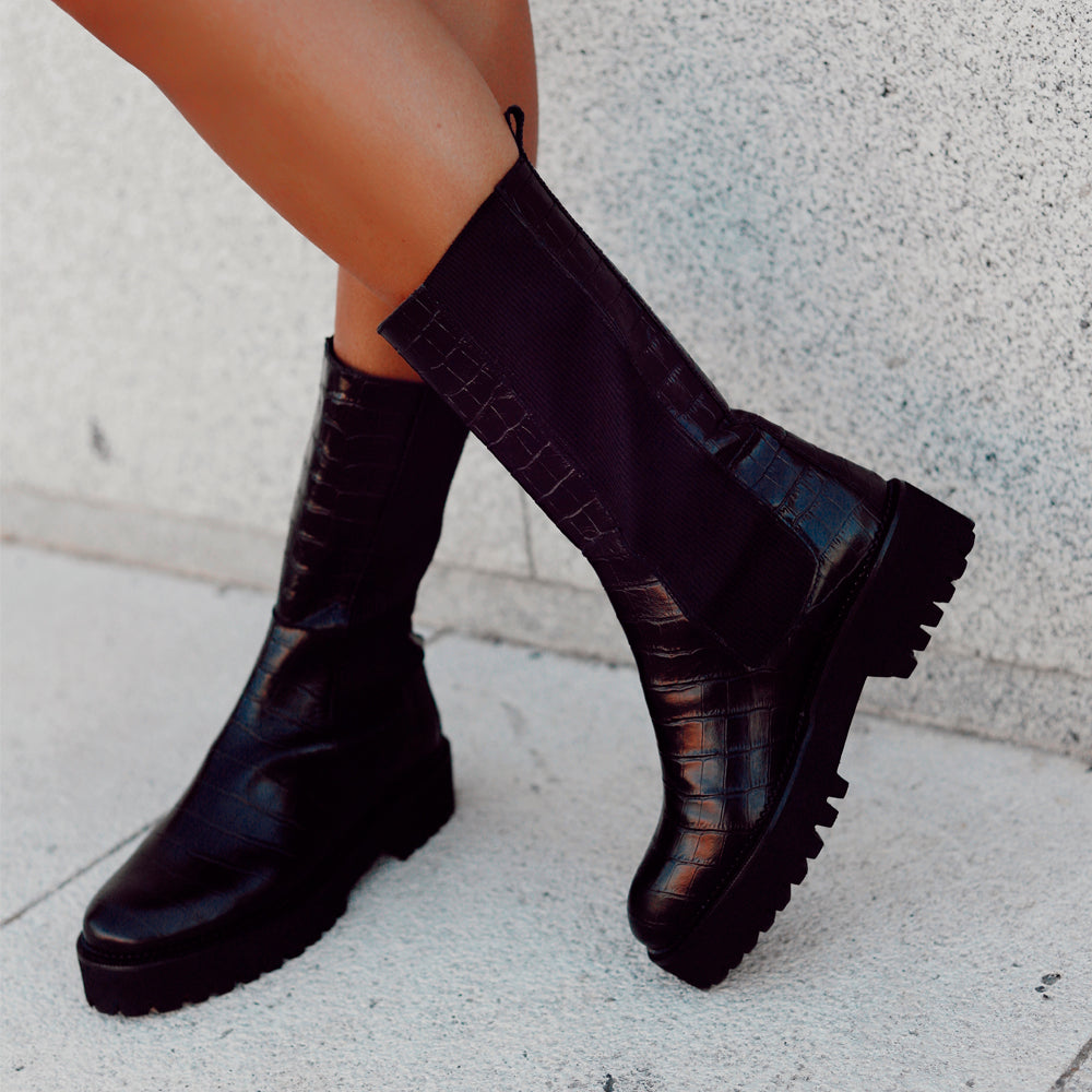 Mujer con unas botas negras moteras en color negro efecto cocodrilo