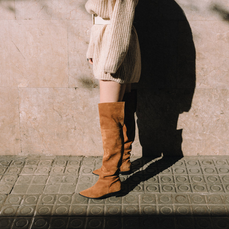 Mujer posando de perfil con unas botas de caña alta tipo mosquetera en color marrón