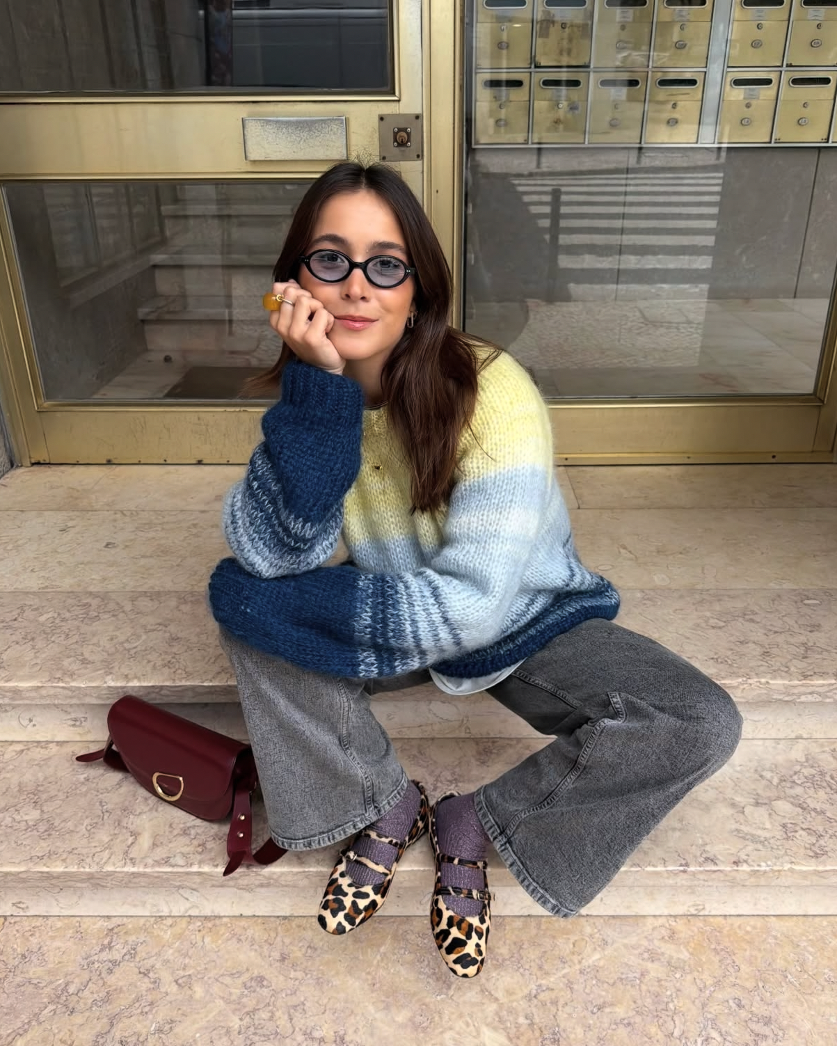 Chica sentada con unas bailarinas en piel efecto leopardo de punta redonda con cierre de habillas en las dos tiras de la parte de arriba