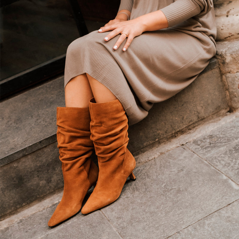 Chica sentada con vestido beige y botines en ante marrón