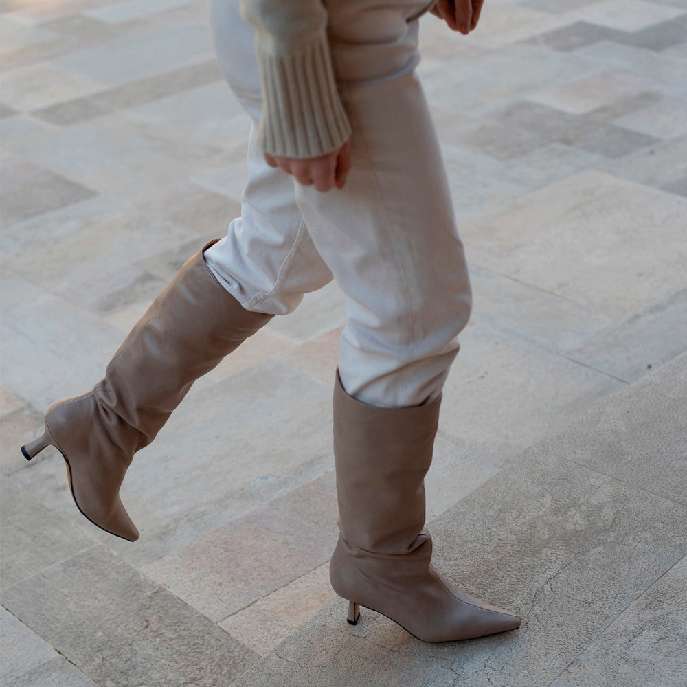 Bota de caña alta para mujer, con tacón en piel nude, atemporal y elegante.
