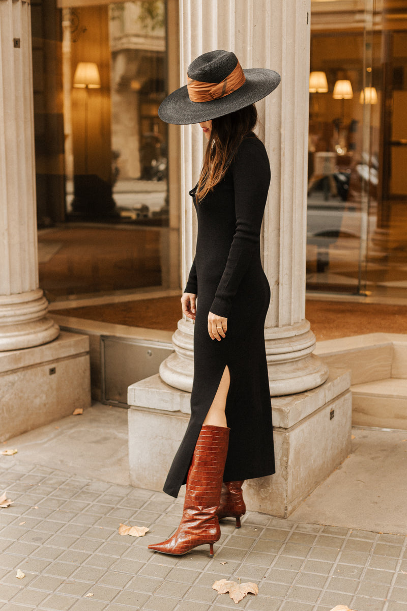 Chica con sombrero, vestido negro y botas de tacón marrones efecto cocodrilo